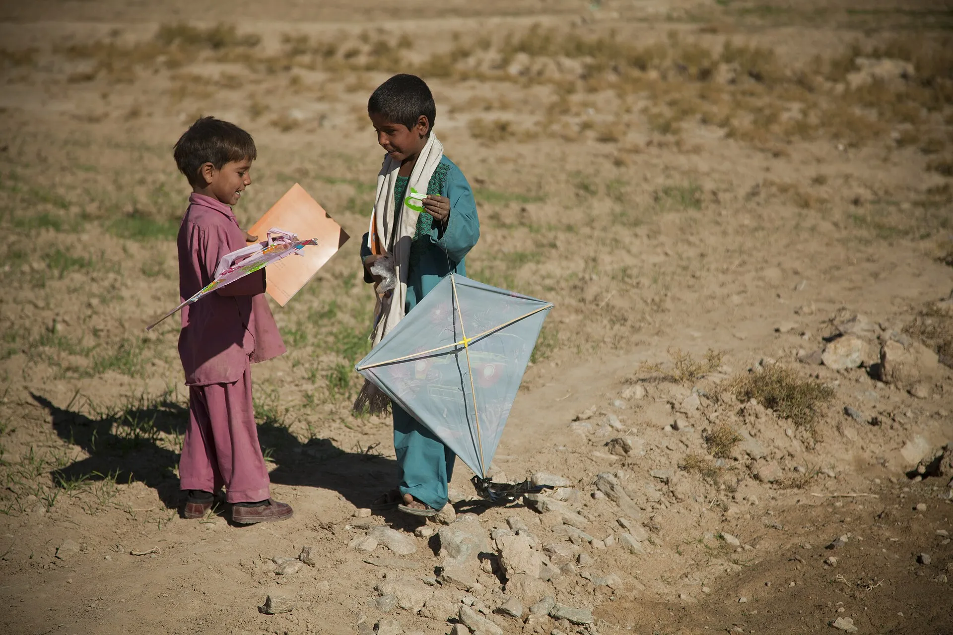 Two boys hold handmade paper kites — sticks, plastic sheeting and string (file photo, Afghanistan, 2012). Kites of this simple kind are the toys at the centre of the Israeli directive described in this article. This photo does not depict Gaza or the events reported.