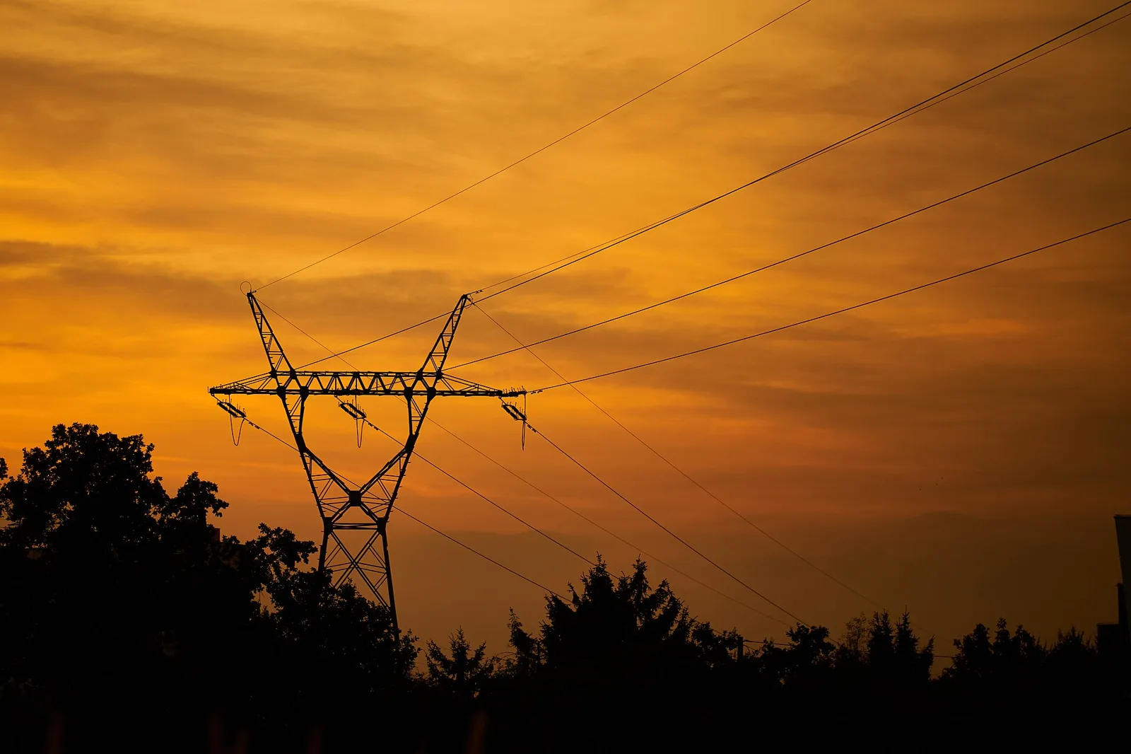 An electricity transmission tower silhouetted at sunset (file photo). Ukraine's energy ministry says Russia's October campaign against power plants and transmission systems has spread to western regions. This photo does not depict any facility reported in this article.