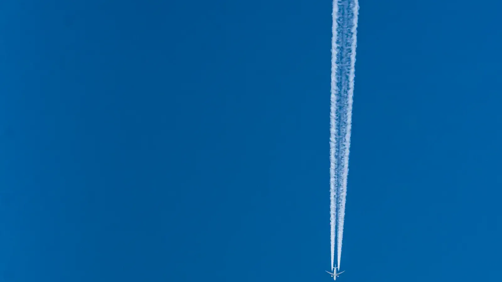 A high-altitude aircraft leaving a contrail across a clear sky.