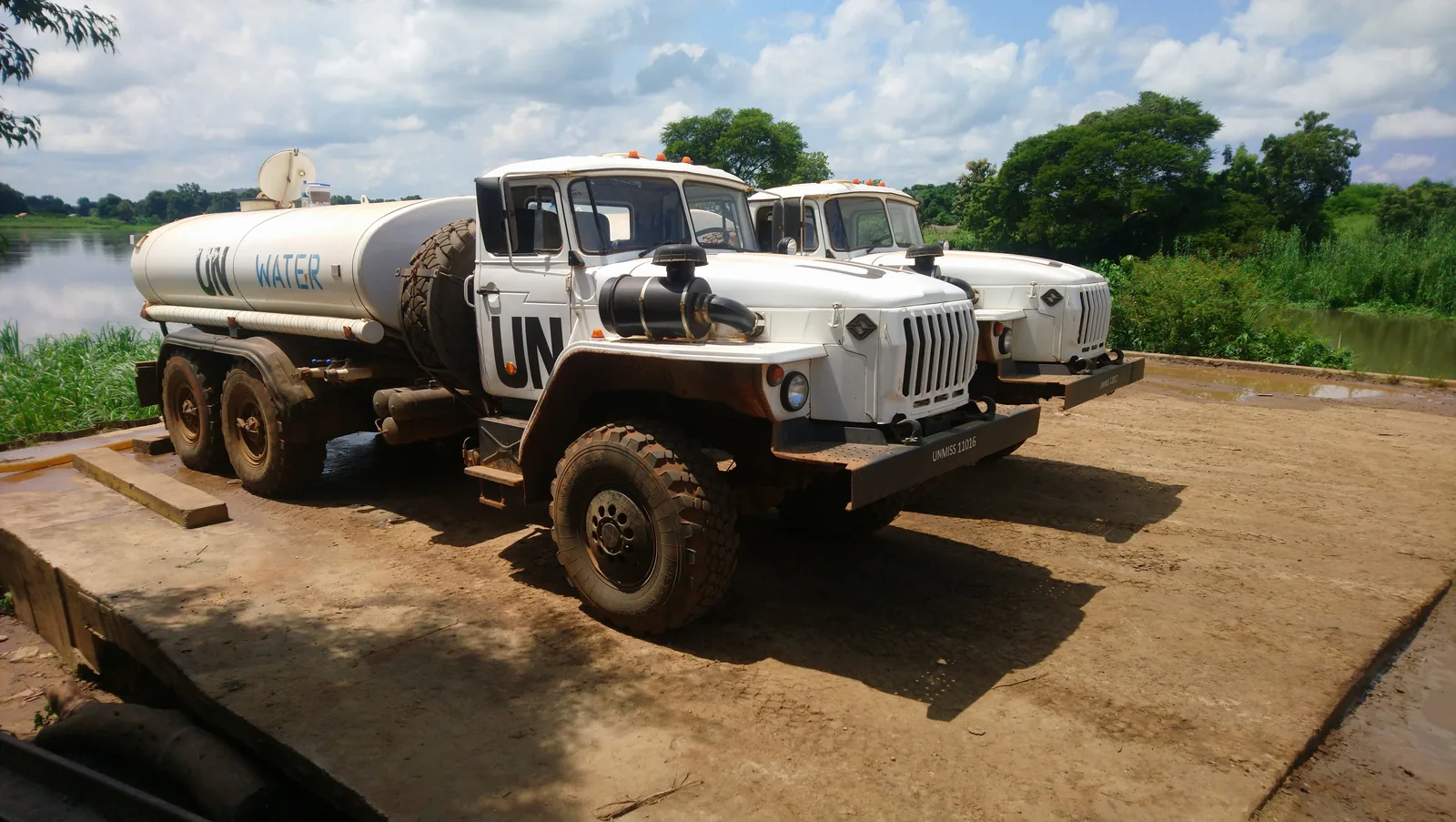 Two UN-marked water tanker trucks of the UN Mission in South Sudan (UNMISS) collecting drinking water from the Nile — non-combat humanitarian logistics. Generic file photo. — Image: Besserwisser123 / Wikimedia Commons (CC BY-SA 4.0)