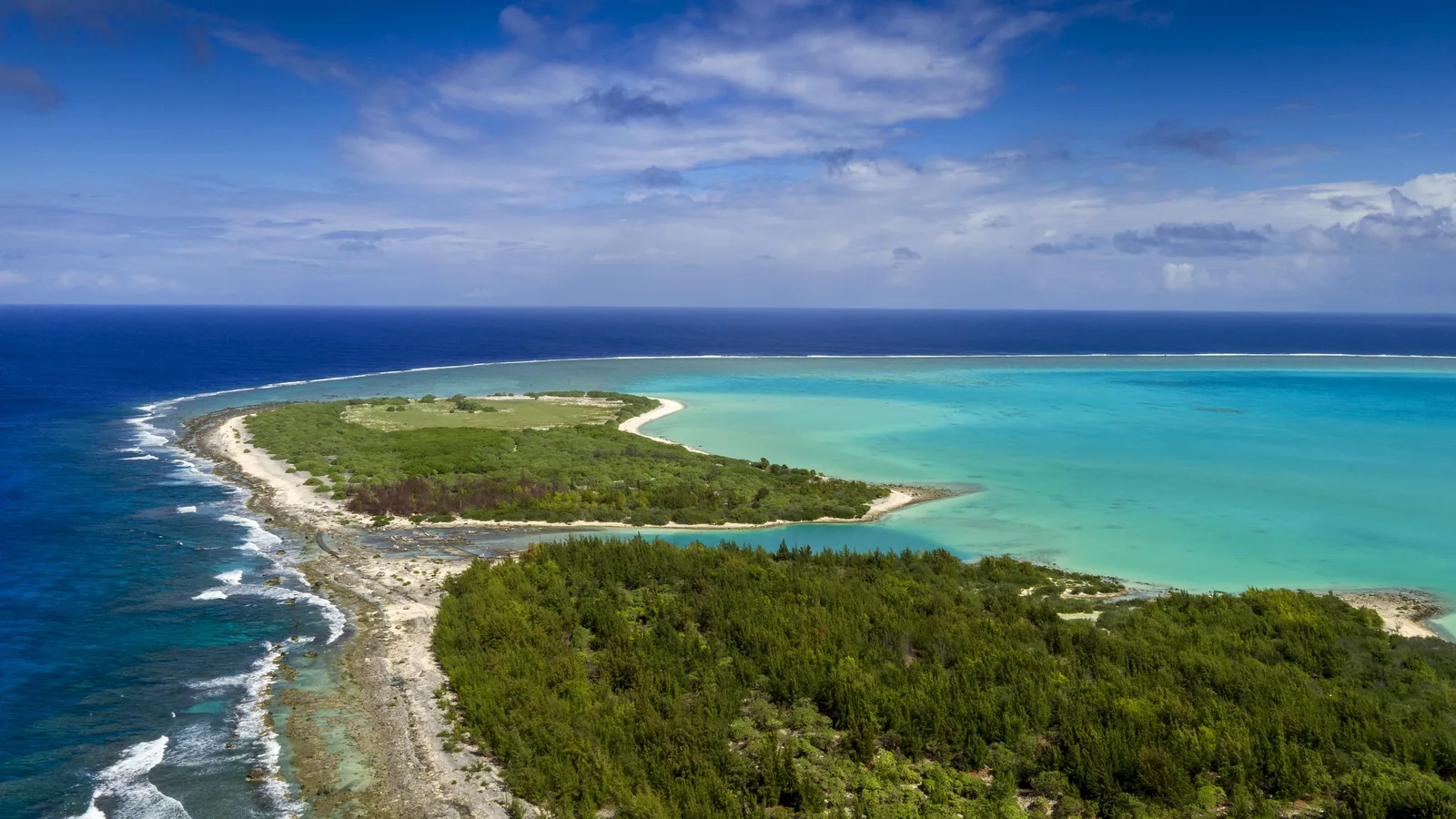 A green island ringed by a turquoise lagoon, seen from above. — Photo: Capt. Anastasia Schmidt / Wikimedia Commons (Public domain)